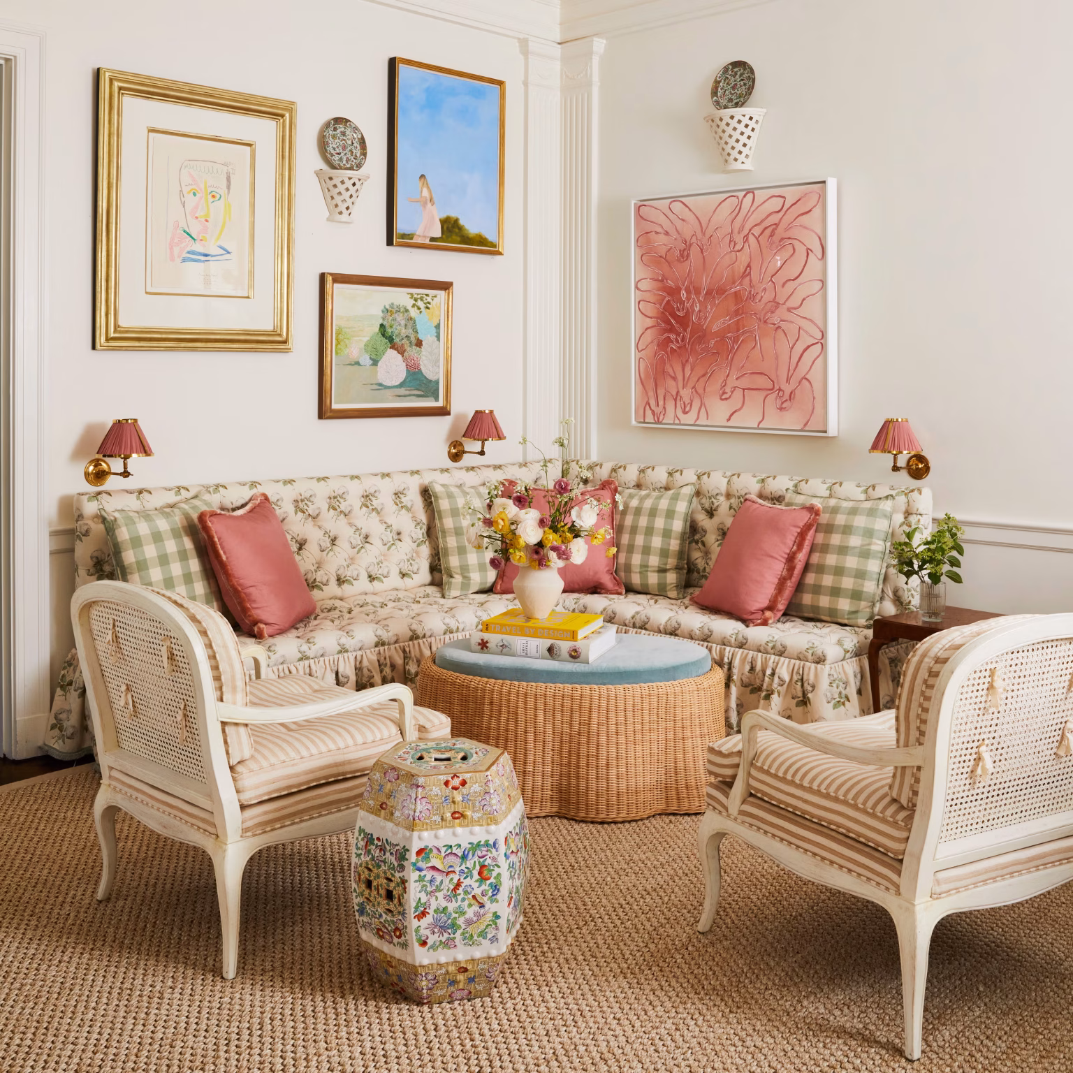 A colorful living room featuring patterned upholstered seating, decorative lighting, framed artwork, traditional furniture and layered accessories that create an elegant designer interior.